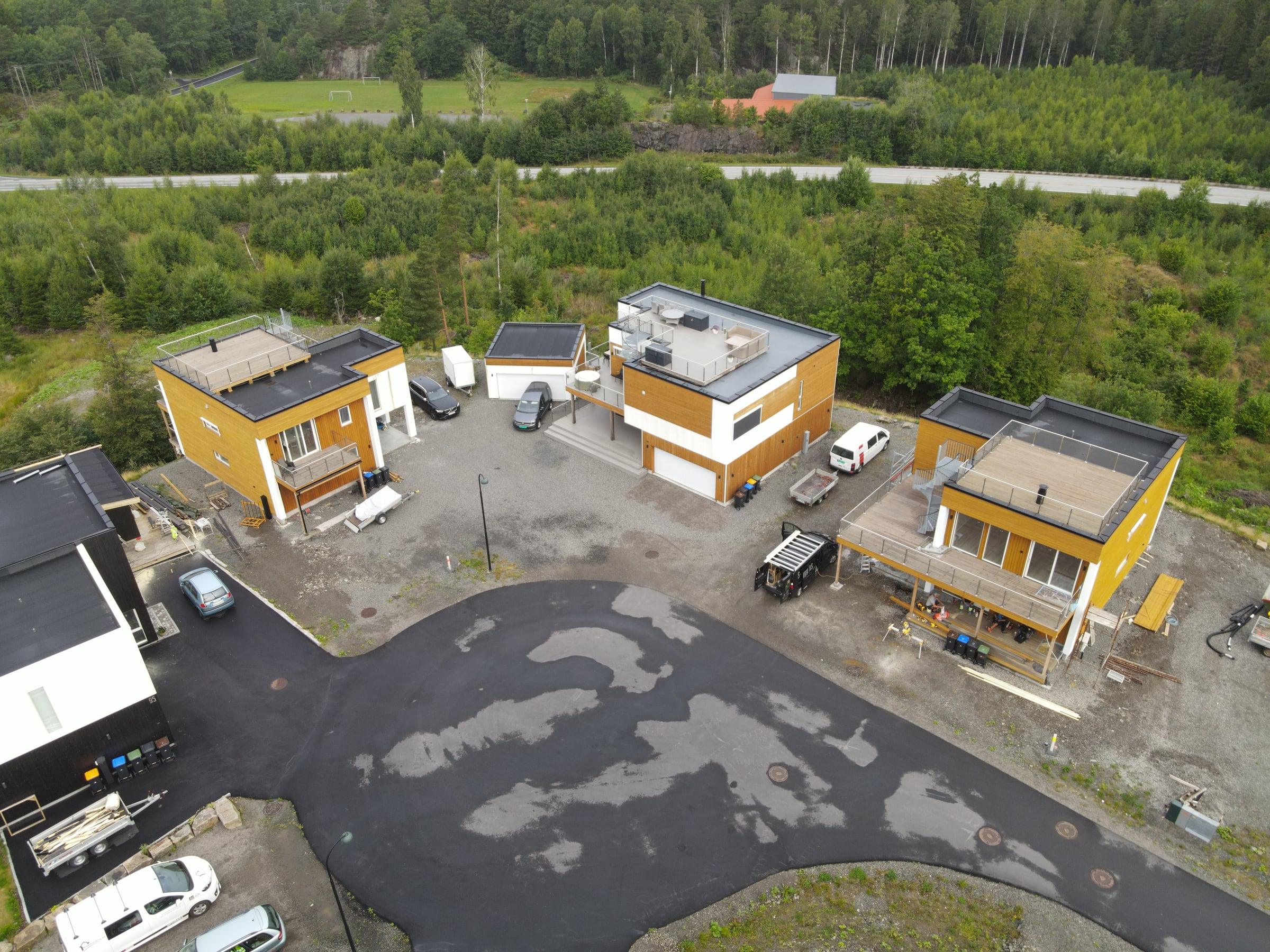 Tre funkisboliger med flate tak og trekledning rundt en ny vei