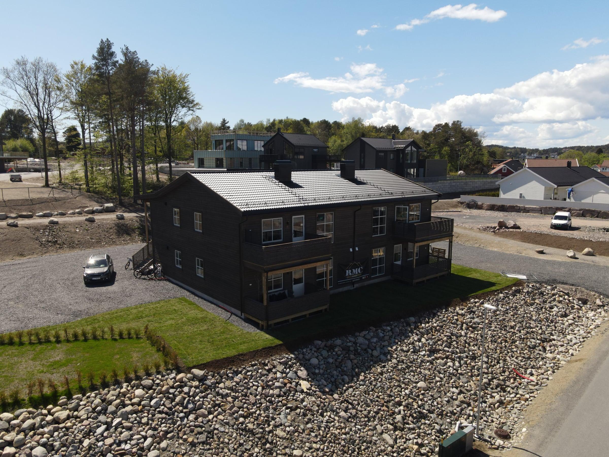 Mørk 4-mannsbolig på en ny tomt med steinfylling, sett fra drone